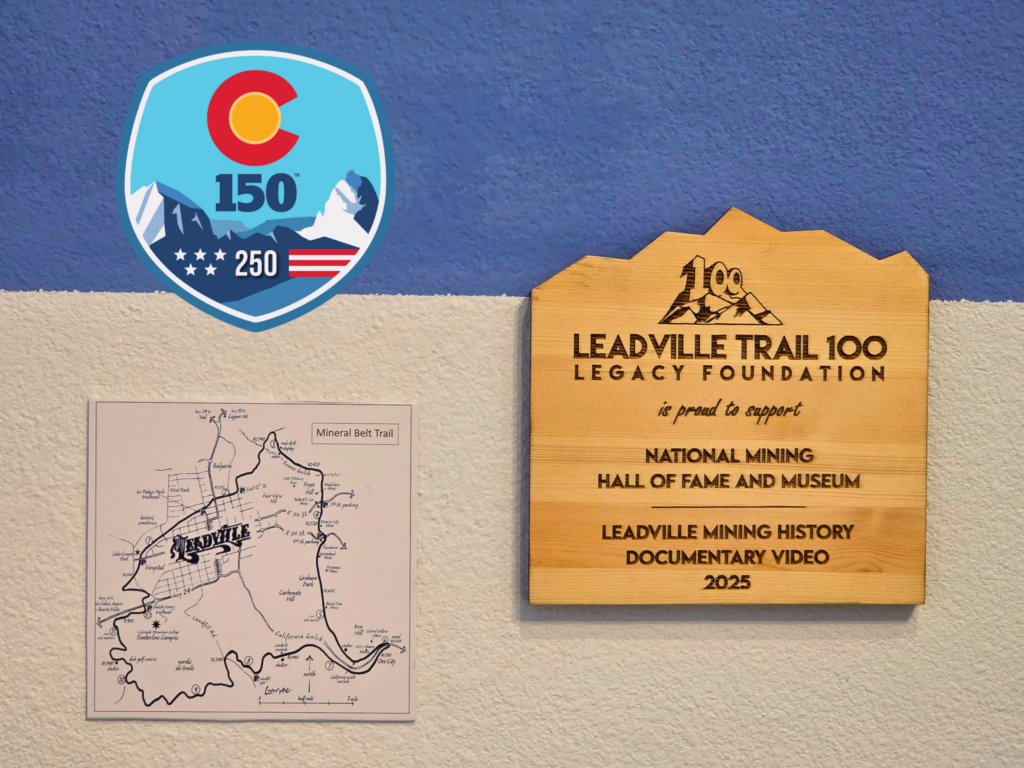 image of the Colorado 150, America 250 logo, a map of the Leadville, Colorado Mineral Belt Trail, and a wooden plaque recognizing the Leadville Trail 100 Foundation for awarding a grant to the exhibit